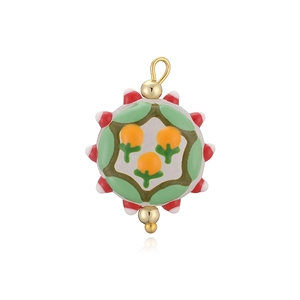 Détail du pendentif en émail rond avec motif floral orange et anneau en métal doré