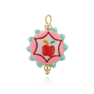 Vue détaillée d'un pendentif en émail avec pomme rouge et bordure dorée colorée