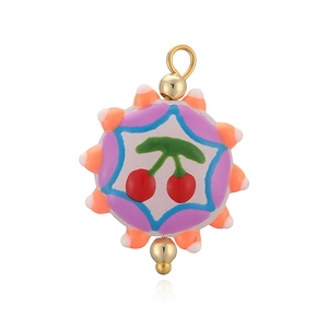 Gros plan détaillé d'un pendentif rond en émail coloré avec motif cerise et perles dorées