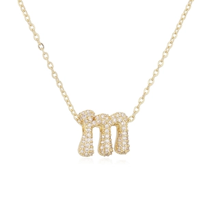 Detailaufnahme der goldenen Kette mit m-Buchstaben-Anhänger und glänzenden Zirkonia