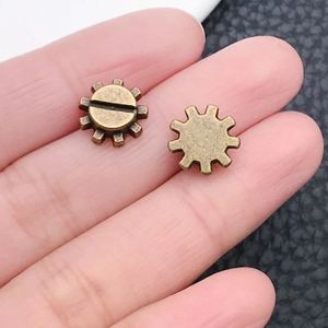 Close-up of small vintage bronze alloy gears on a fingertip for DIY steampunk crafts