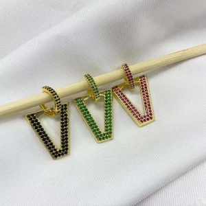 Detail of geometric V-shaped hoop earrings with black, green, and pink crystals