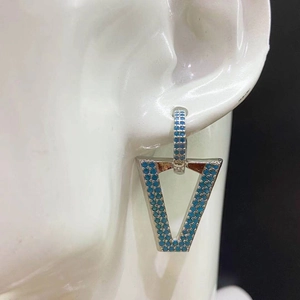 Macro shot of silver V-shaped geometric earrings with turquoise pave on model ear