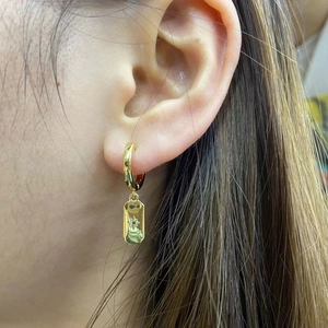 Detail of 18K gold plated earring with rectangular charm, star pattern and blue stone