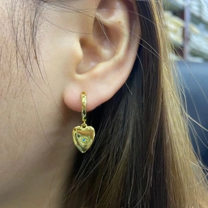 Close-up of 18K gold-plated heart earrings featuring a centered blue zircon stone inlay