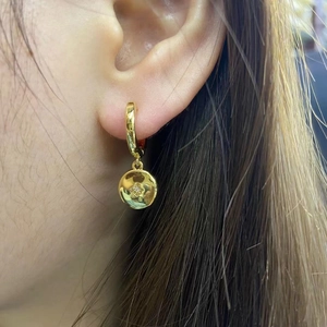 Detailed view of 18K gold plated hoop earring with star engraved round pendant and zircon