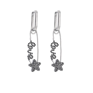 Detail view of silver safety pin earrings with black stones spelling Love and a star
