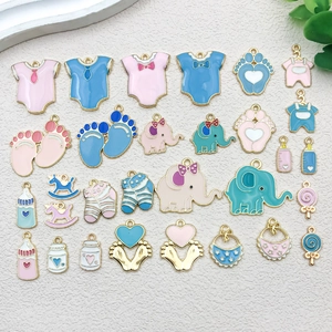 Vista de detalle de colgantes esmaltados con temática de bebé en rosa y azul pastel