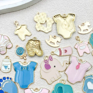 Detalle de dijes de esmalte en colores pastel con temática de bebé y biberones variados