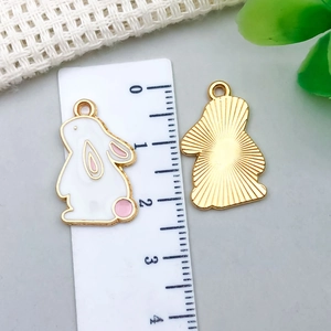 Detailed macro view of cute pink rabbit alloy charm with golden enamel finish and size ruler
