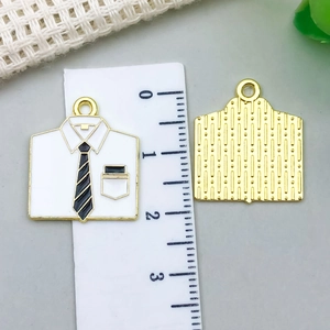 Detail of shirt shaped alloy pendant with black tie and gold edges on a ruler