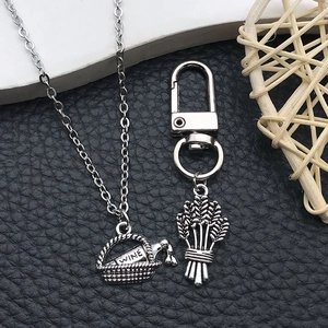 Macro detail of vintage silver wine bottle basket pendant and wheat ear charm on a chain
