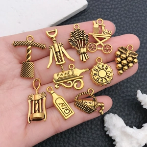 Vintage gold alloy wine themed charms set with corkscrew and grapes on leather background