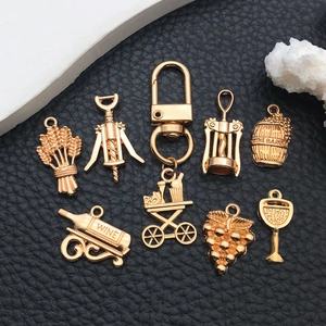 Detail of 9-piece gold alloy wine and grape charms set on black leather background