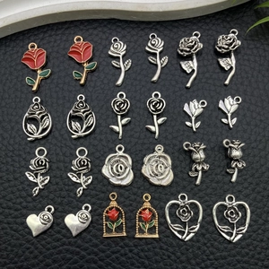 Flat lay of diverse rose enamel and alloy charms for DIY jewelry on black leather