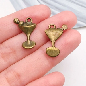 Macro view of a vintage bronze cocktail glass pendant charm held between fingers for size