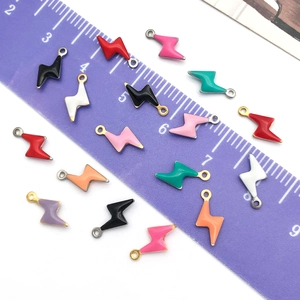 Macro shot of colorful enamel lightning bolt charms with ruler showing 10mm size scale