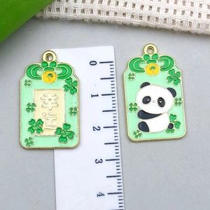Detailed view of 2.5cm panda and clover lucky charms with green enamel finish and ruler