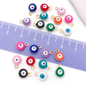 Macro detail of 8mm gold-plated evil eye charms in various colors with measurement scale