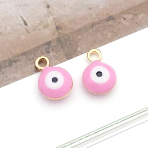 Detailed macro view of two pink evil eye round pendants with golden plated alloy frames