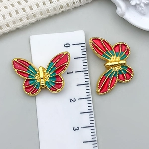 Detailaufnahme von 25mm Gold-Schmetterlingsanhängern mit rotem und grünem Emaille