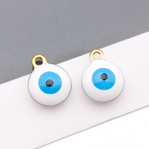 Macro detail of white enamel evil eye pendants with blue iris and golden metal ring