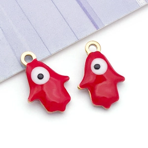 Detailed macro view of two red enamel Hamsa Hand pendants with Evil Eye in golden finish