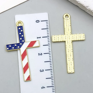Detail of 4cm American flag cross pendant with golden back and ruler for size reference