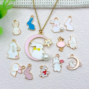 Detail of colorful enamel rabbit charms with moon and flower motifs on textured fabric