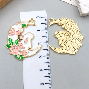 Detail of enamel rabbit moon pendants with cherry blossom design and gold textured back