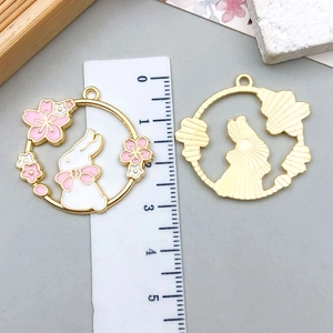 Detail of bunny and cherry blossom enamel charms with a ruler showing 3.3cm size