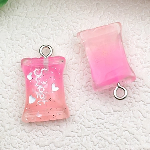 Macro detail of pink gradient resin candy bag pendants with glitter and Sweet text