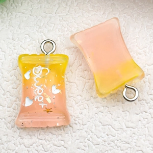 Macro shot of orange gradient resin candy pendants with Sweet text and silver loops
