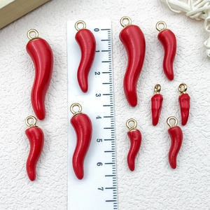 Red 3D chili pepper pendants in four sizes with gold loops on textured white leather