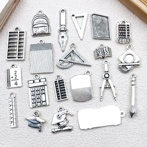 Detailed view of silver school-themed charms including ruler pen and graduation cap