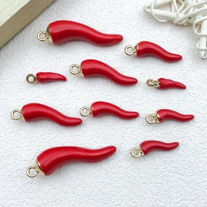 Detailed view of red enamel chili charms in multiple sizes with gold hanging loops