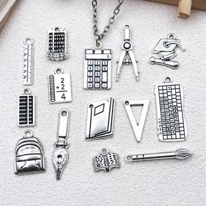 Macro view of antique silver school charms including ruler calculator and book pendants