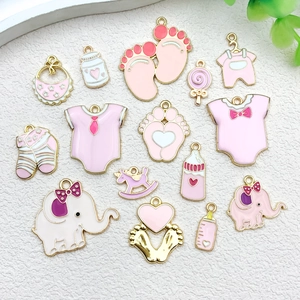 Vista plana de dijes esmaltados en rosa y lila con motivos de bebé para joyas DIY