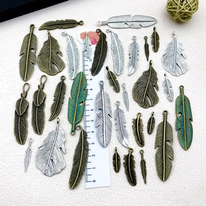 Macro view of vintage zinc alloy feather charms in various sizes with a scale ruler