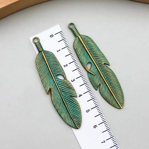 Detailed macro view of retro bronze feather pendants with green patina finish and leaf texture