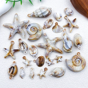 Detailed view of DIY shell and starfish charms for jewelry making on sandy background