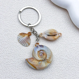 Detailed view of beige acrylic seashell and conch pendants on a gold keychain link