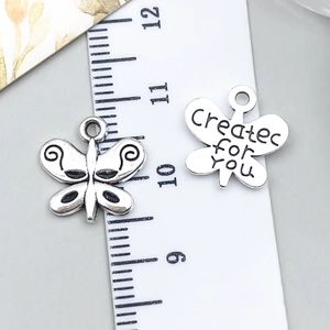 Detailed macro view of retro silver butterfly charms showing size and created for you text