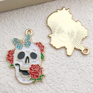 Detail of Halloween skull pendant with red roses and teal butterfly on a golden base