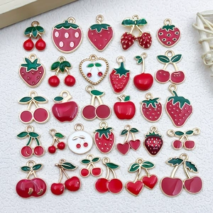Macro detail of red enamel fruit charms including cherry and strawberry for DIY jewelry