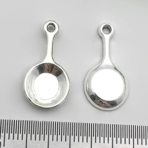 Detailed view of silver frying pan pendants for DIY jewelry making with ruler scale
