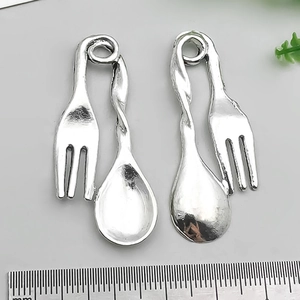 Macro view of vintage silver alloy spoon and fork pendants with measurement scale