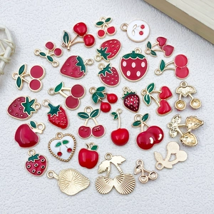 Detailed view of DIY fruit alloy pendants with red and green enamel and hanging rings