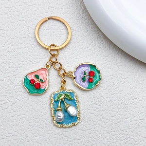 Dettaglio di ciondoli ciliegia da giardino con perle e strass su portachiavi dorati