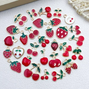 Macro detail of alloy fruit pendants with red strawberry and cherry enamel charms